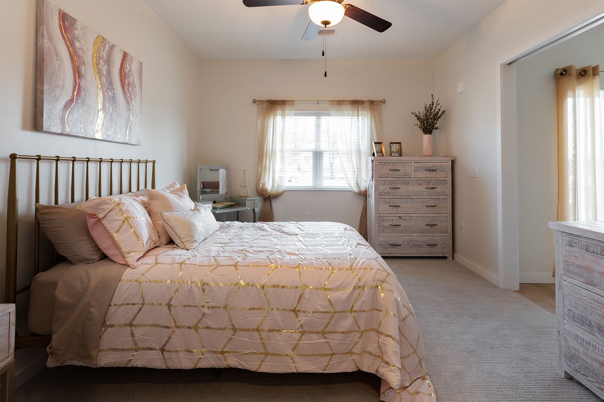 A cozy bedroom with a double bed, a dresser, and a ceiling fan.