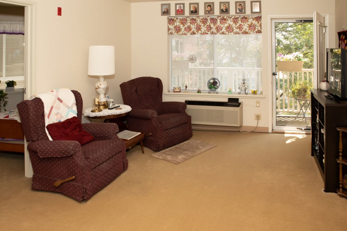 A cozy living room with two brown chairs, a lamp, and a decorated window.