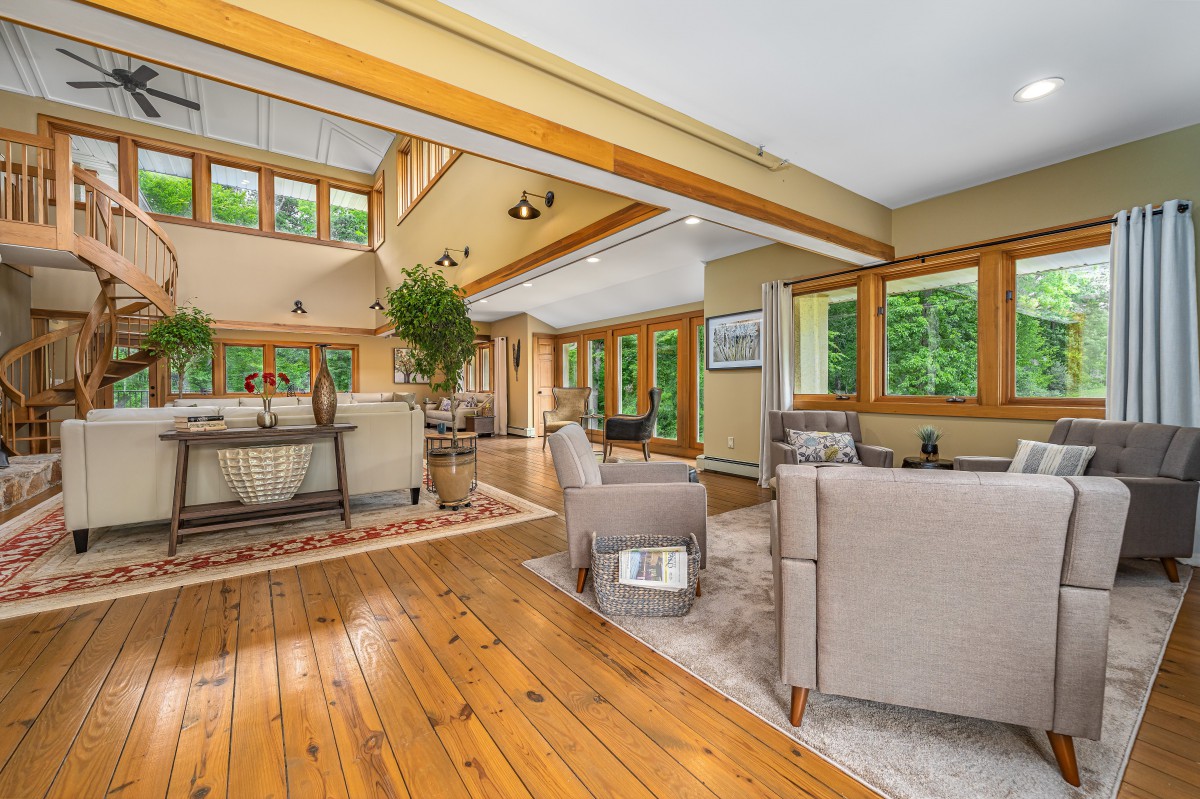 A spacious living room with modern furniture, large windows, and wood flooring.