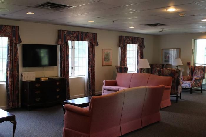 A cozy living room with sofas, a television, and large windows.