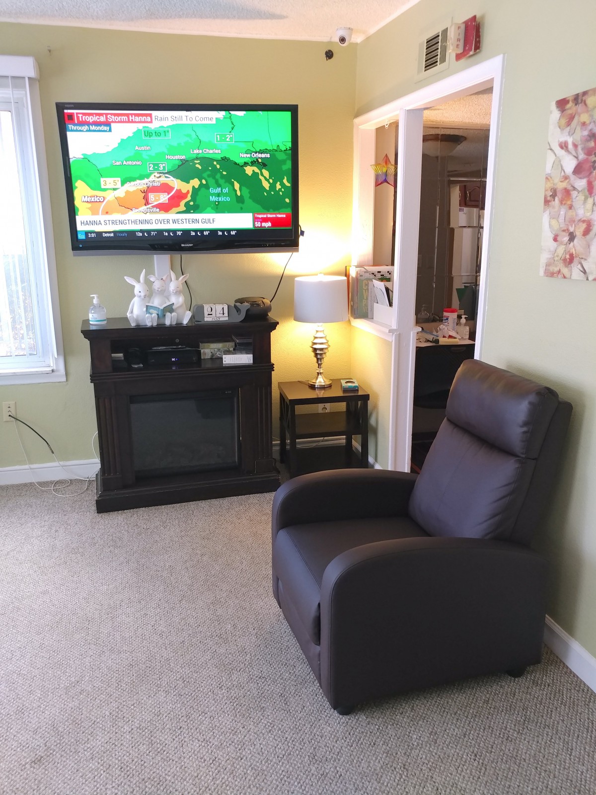A cozy living room with a television, recliner chair, fireplace, and a lamp.