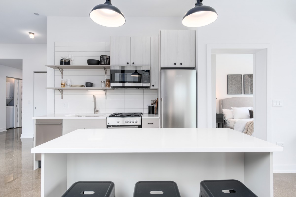 A sleek and modern kitchen featuring minimalist design with white decor and stainless steel appliances.