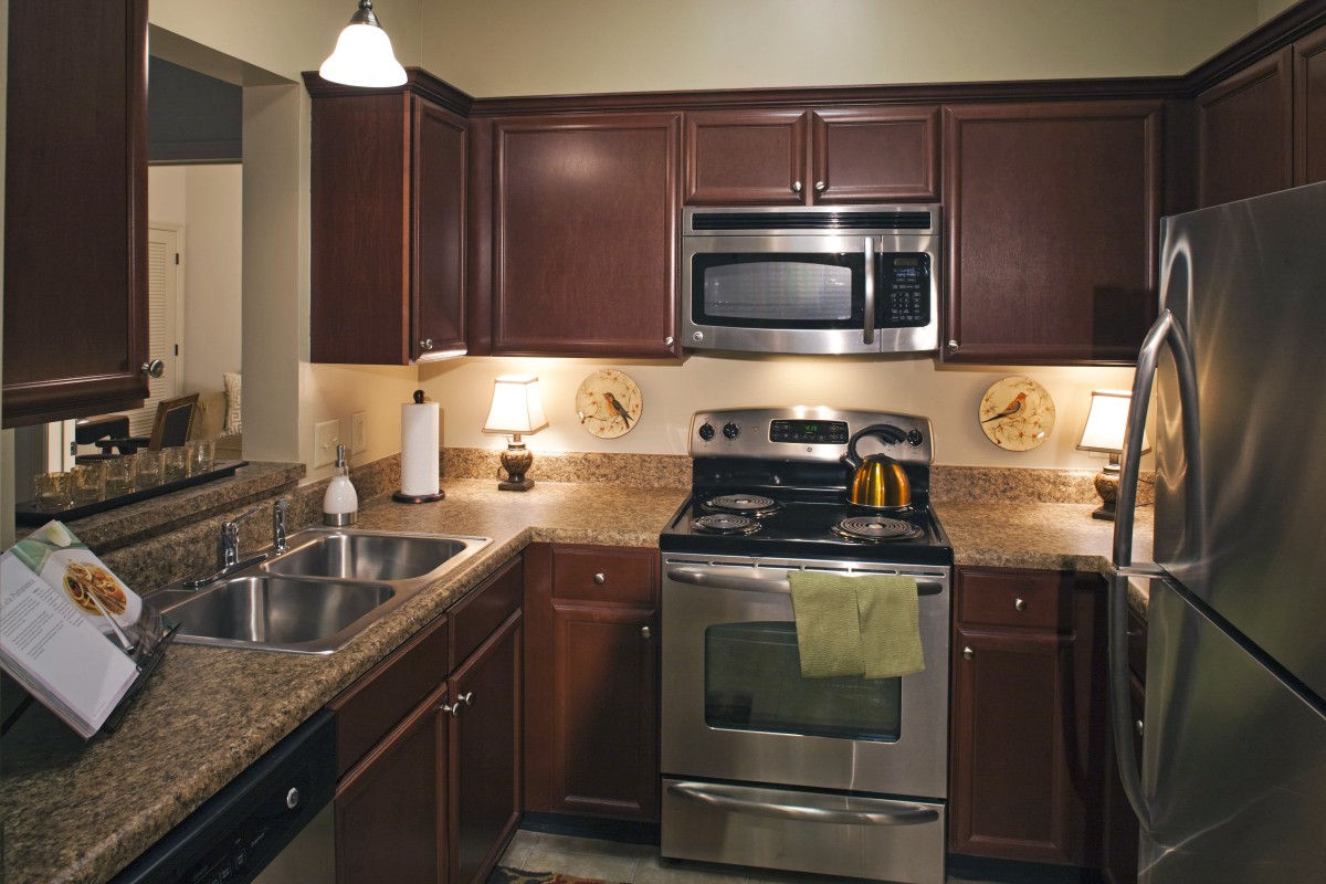 A modern kitchen with dark wood cabinets and stainless steel appliances.