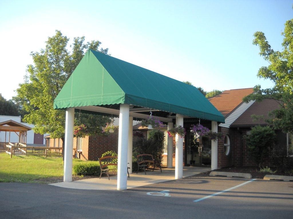 A building entrance with a green canopy supported by white columns.