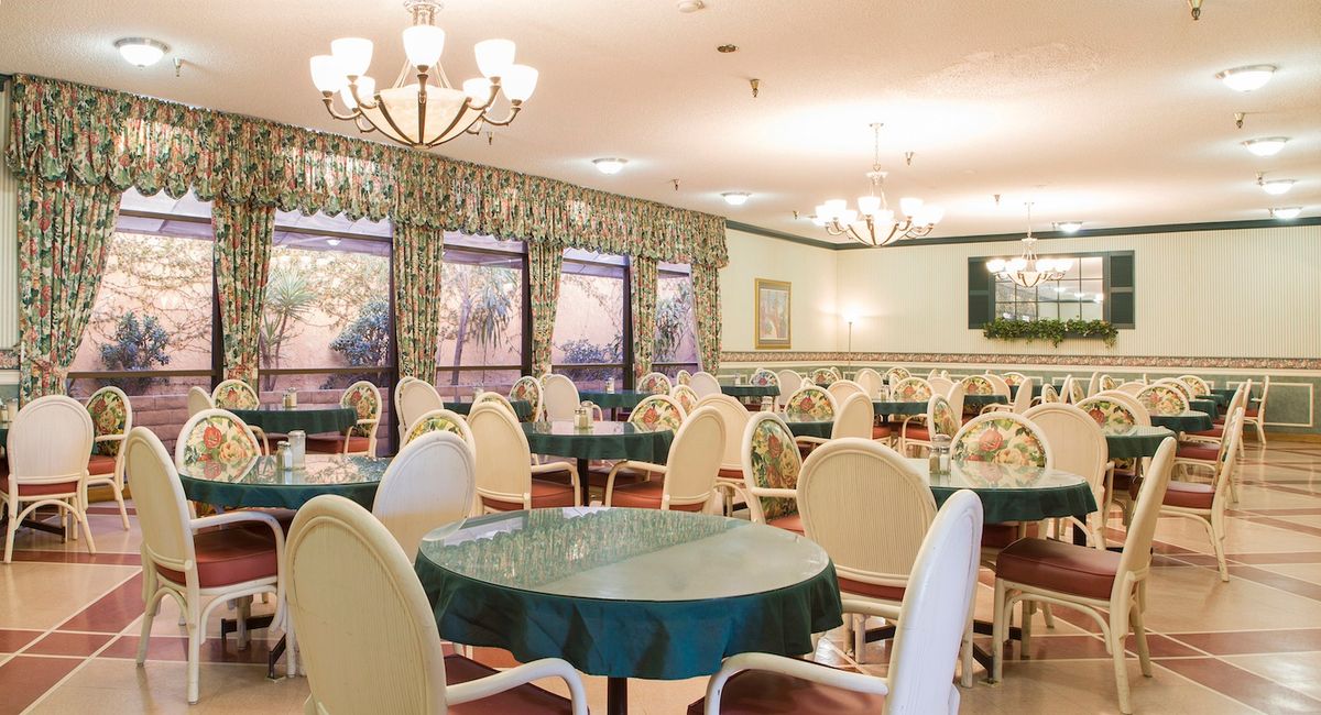 An elegant dining area with round tables, upholstered chairs, and decorative chandeliers.