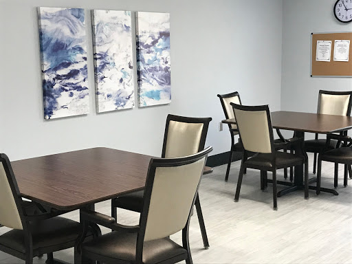 A modern dining area featuring wooden tables and upholstered chairs, complemented by abstract artwork on the walls.