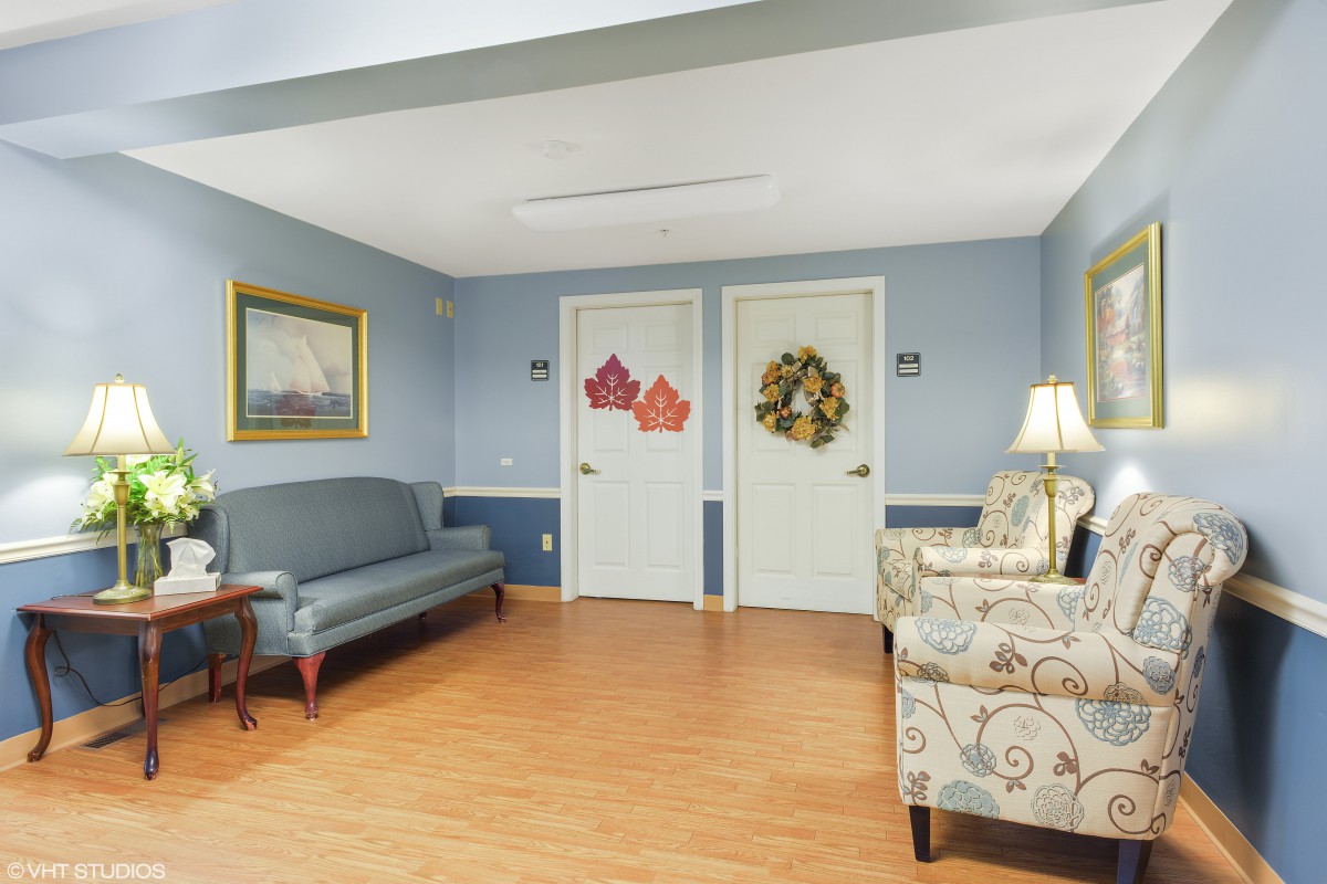 A cozy waiting area featuring a sofa, armchair, and decorated doors.