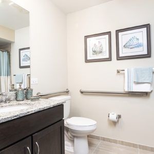 A modern and clean bathroom with a toilet, sink, and neatly arranged towels.