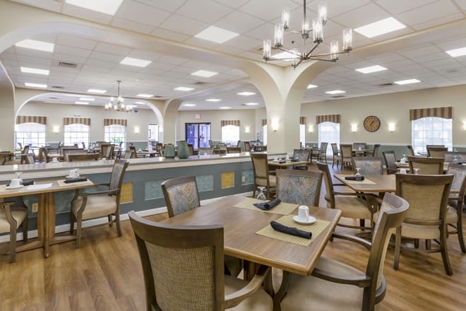 A spacious dining room with elegant furniture and chandeliers.