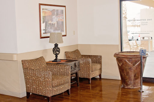 A cozy seating area featuring two wicker chairs, a decorative lamp, and artwork on the wall.