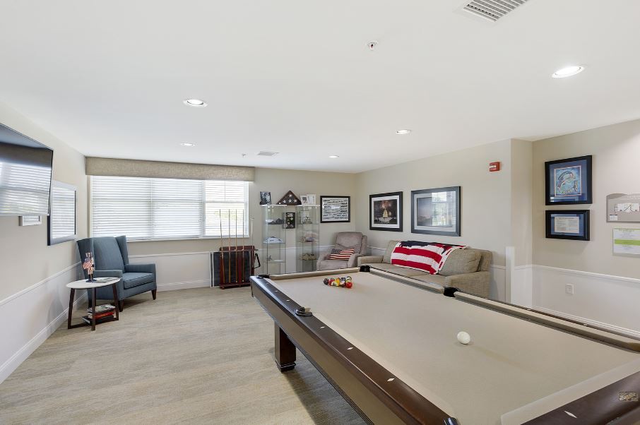 A well-lit game room featuring a pool table and comfortable seating.