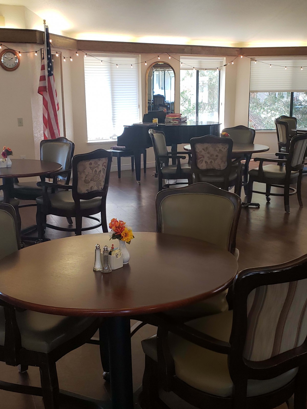 An empty dining area with neatly arranged tables and chairs, featuring a flag and decorative elements.