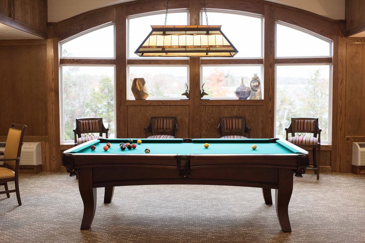 A cozy game room featuring a pool table with wooden furniture and decorative lighting.