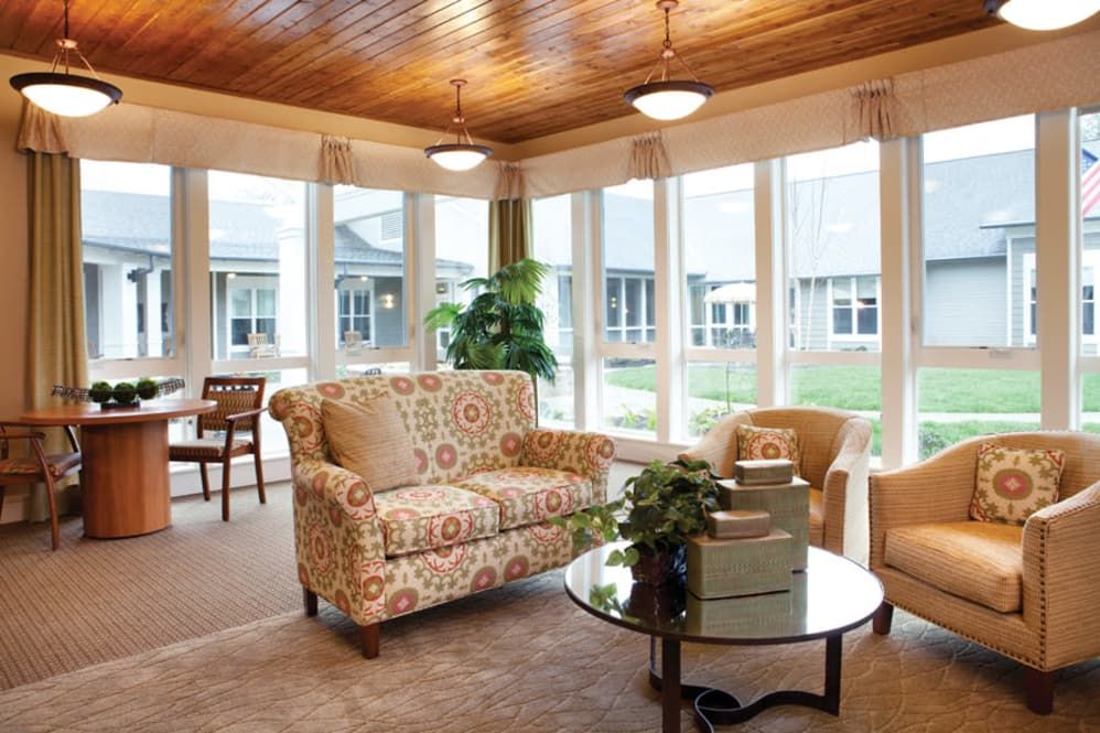 A cozy living room with elegant furniture and abundant natural light through large windows.