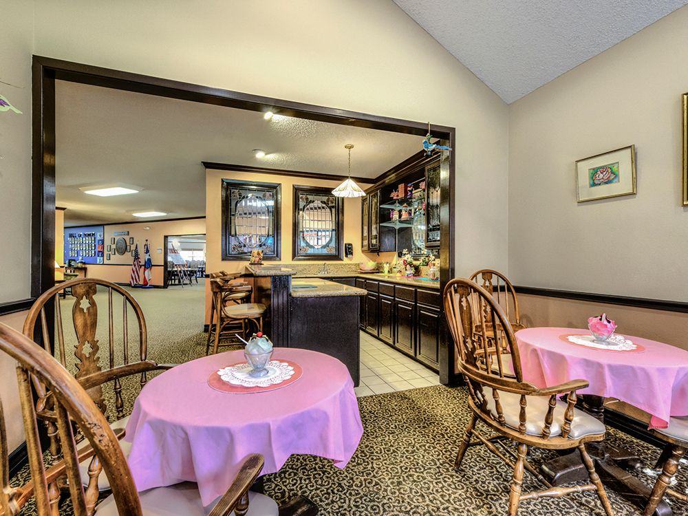 A cozy cafe interior with round tables covered in pink tablecloths and wooden chairs.