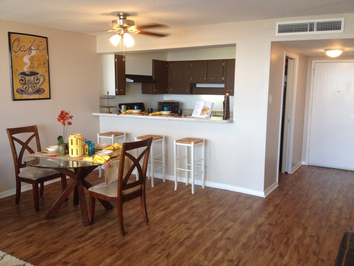 A cozy apartment with an open floor plan featuring a kitchen and dining area with wood flooring.