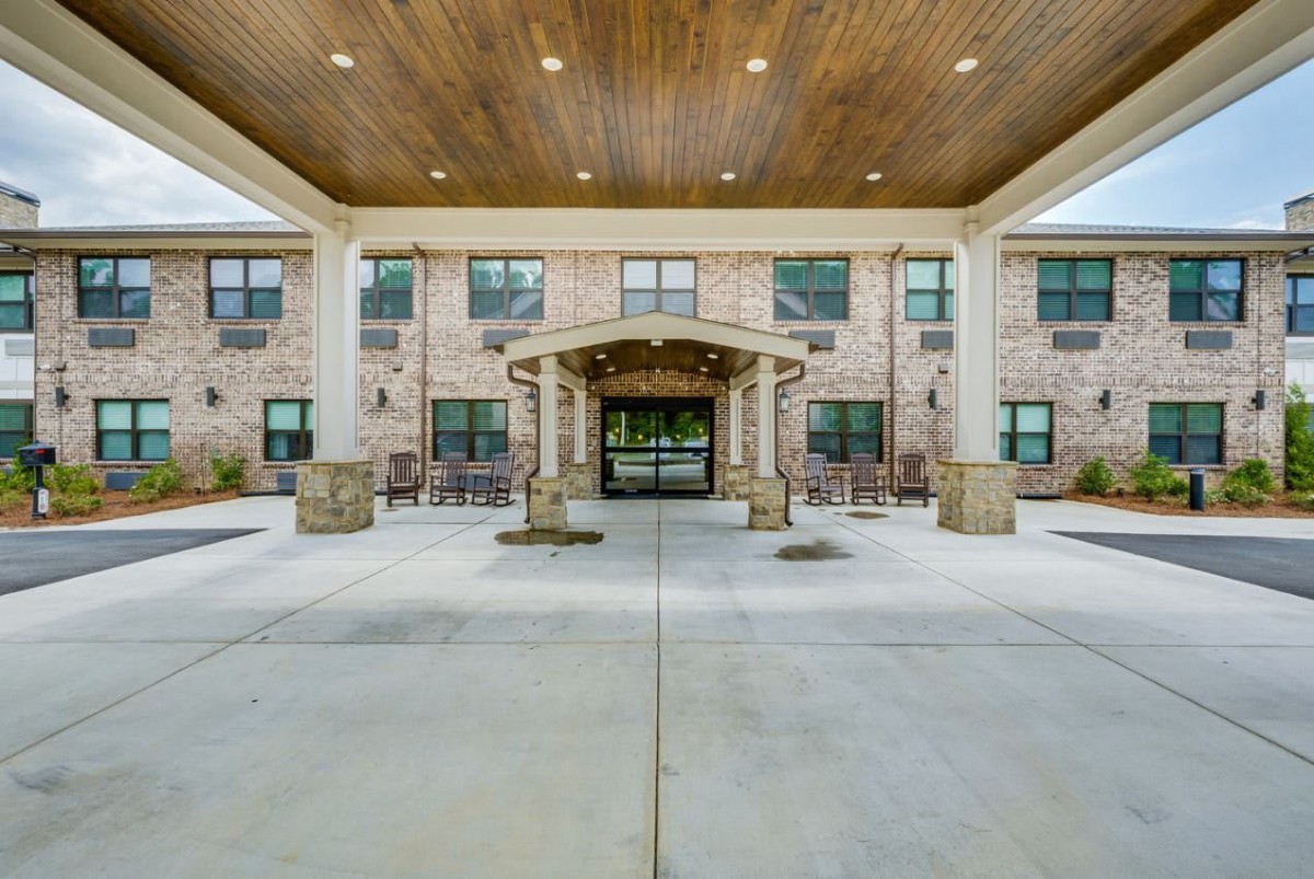 Front entrance of a brick building with a covered walkway and columns.