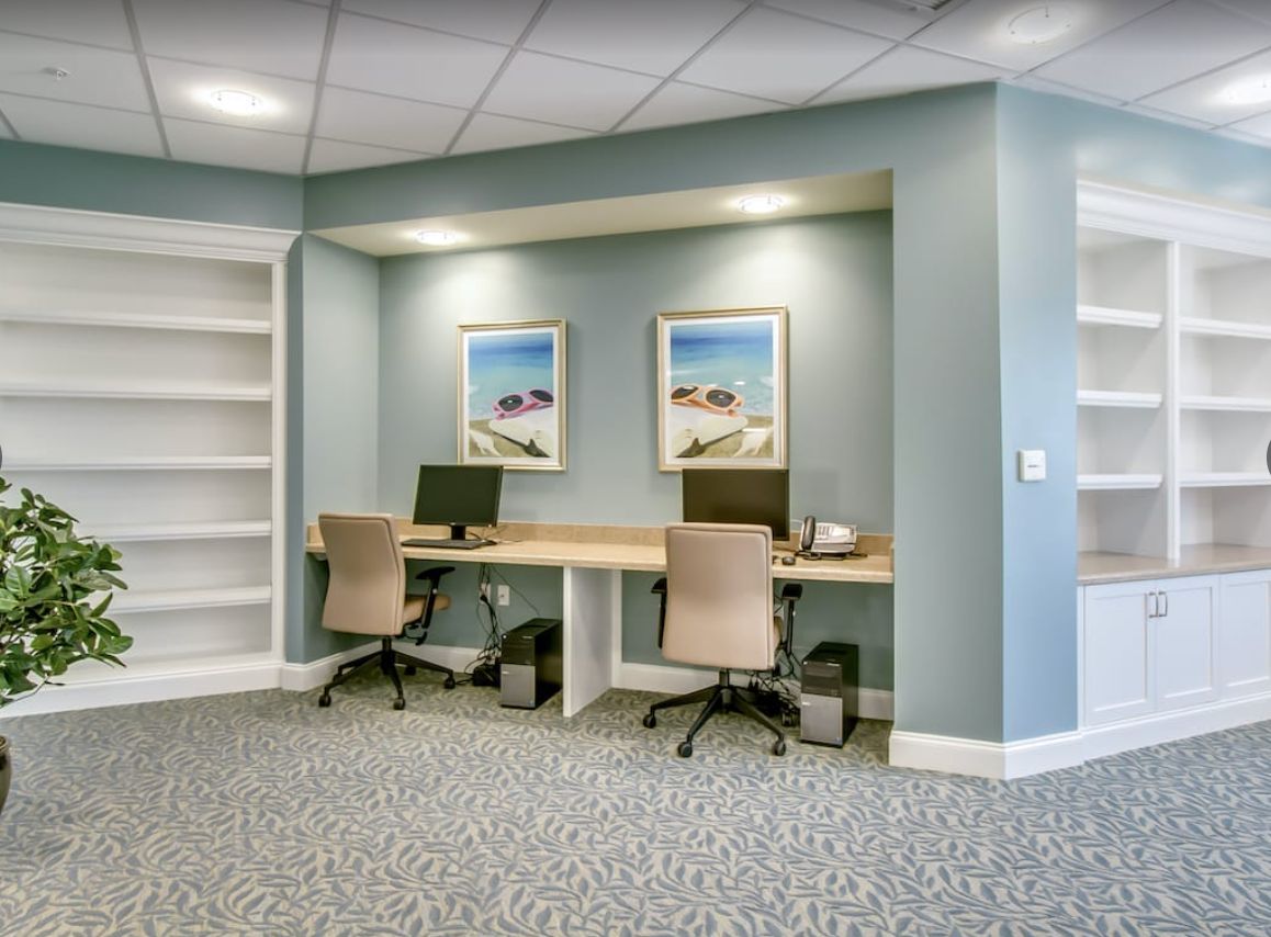 A modern office workspace with two computer stations and built-in shelving.