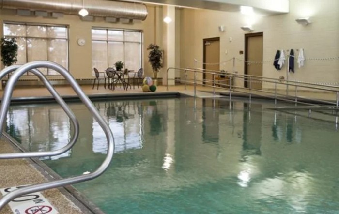 An inviting indoor swimming pool area with seating and warm lighting.