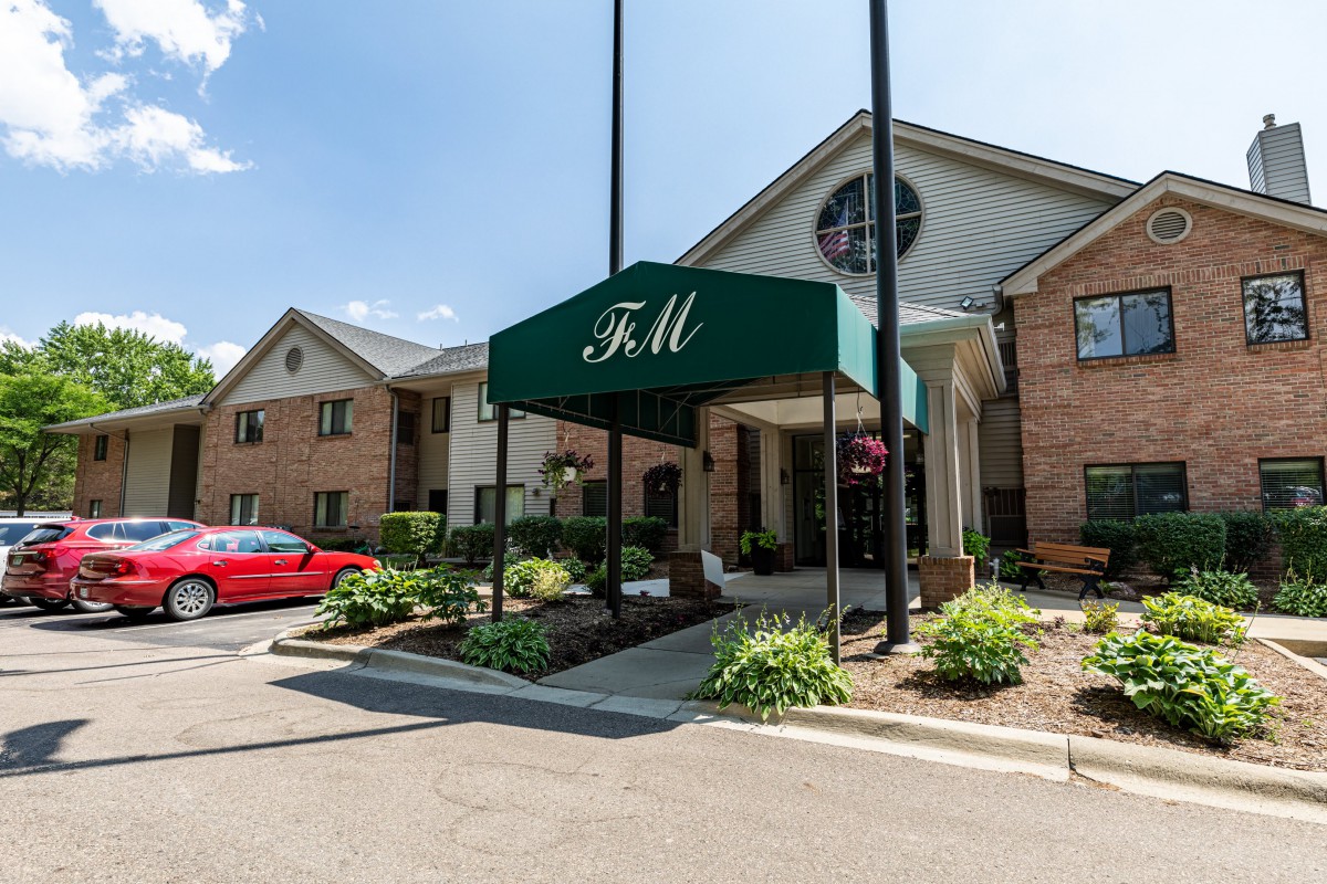 A building entrance with a green awning and surrounding landscaping.