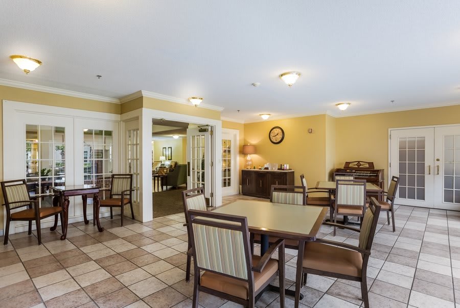 A bright and airy dining area with tables and chairs, featuring yellow walls and a tiled floor.