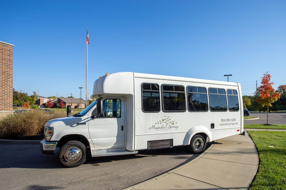 A white shuttle bus parked outdoors under a clear blue sky.