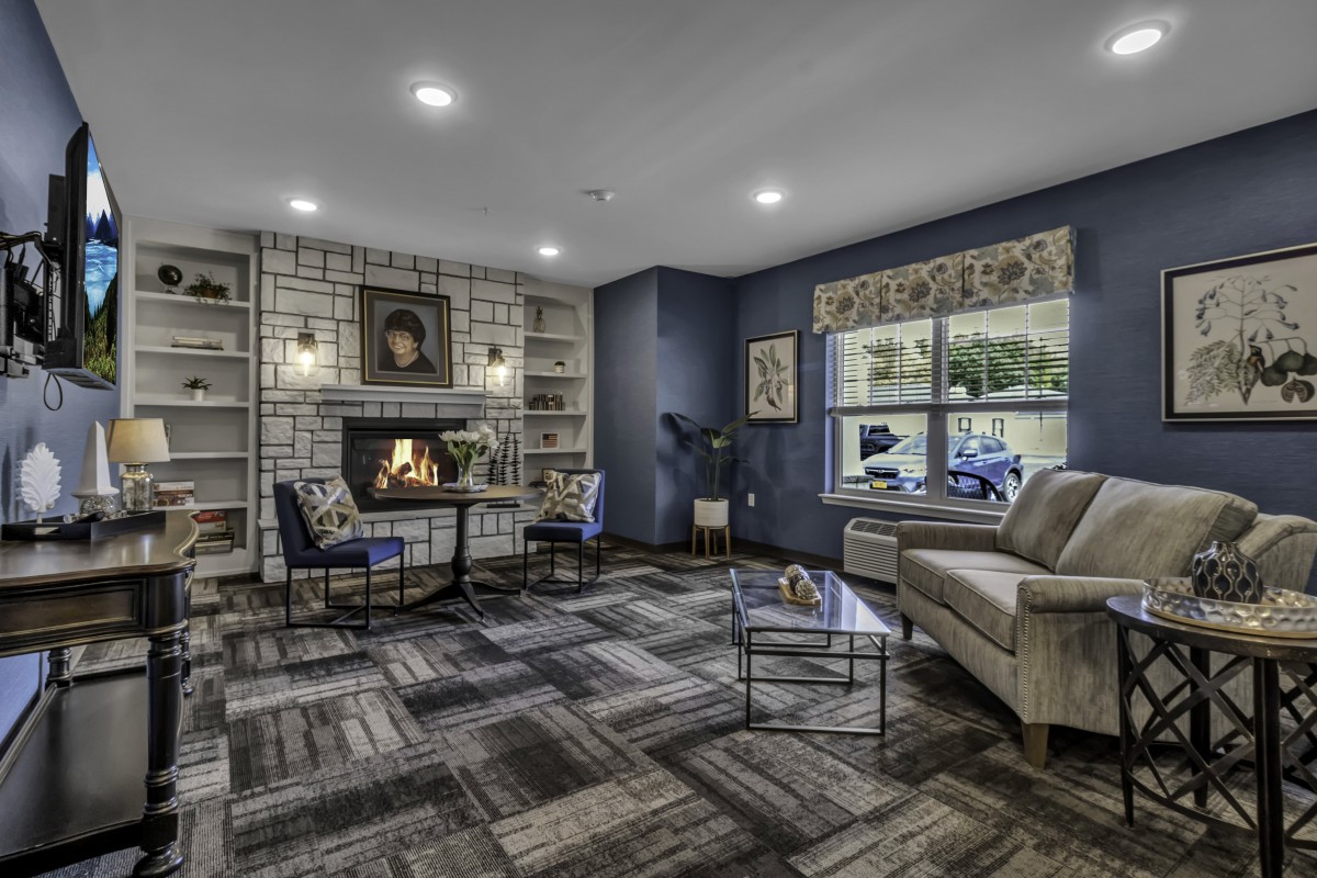 A cozy living room with a fireplace, bookshelves, and comfortable seating.
