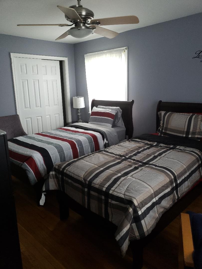A cozy bedroom with two twin beds featuring striped bedding and a lamp by the window.