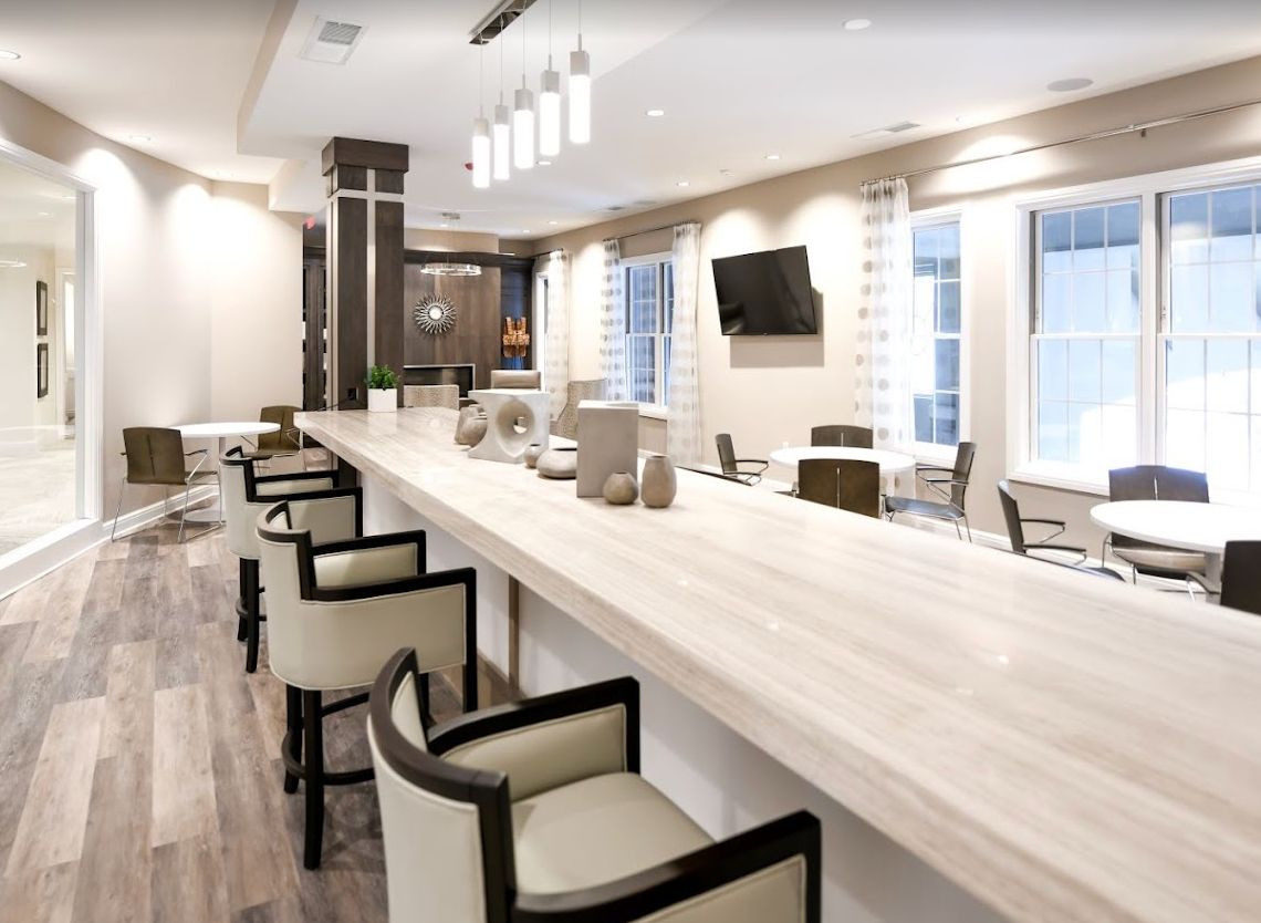 A modern kitchen interior with a long countertop and bar stools.