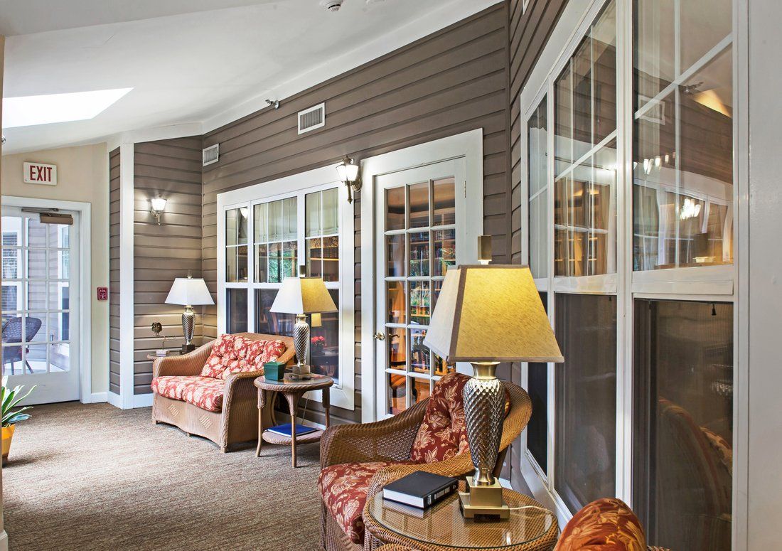A cozy living area featuring comfortable seating, side tables with lamps, and large windows.
