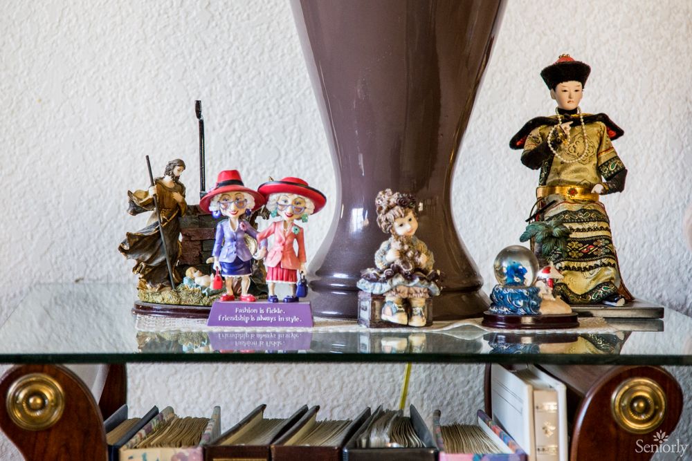 A collection of colorful figurines displayed on a glass shelf in a home setting.