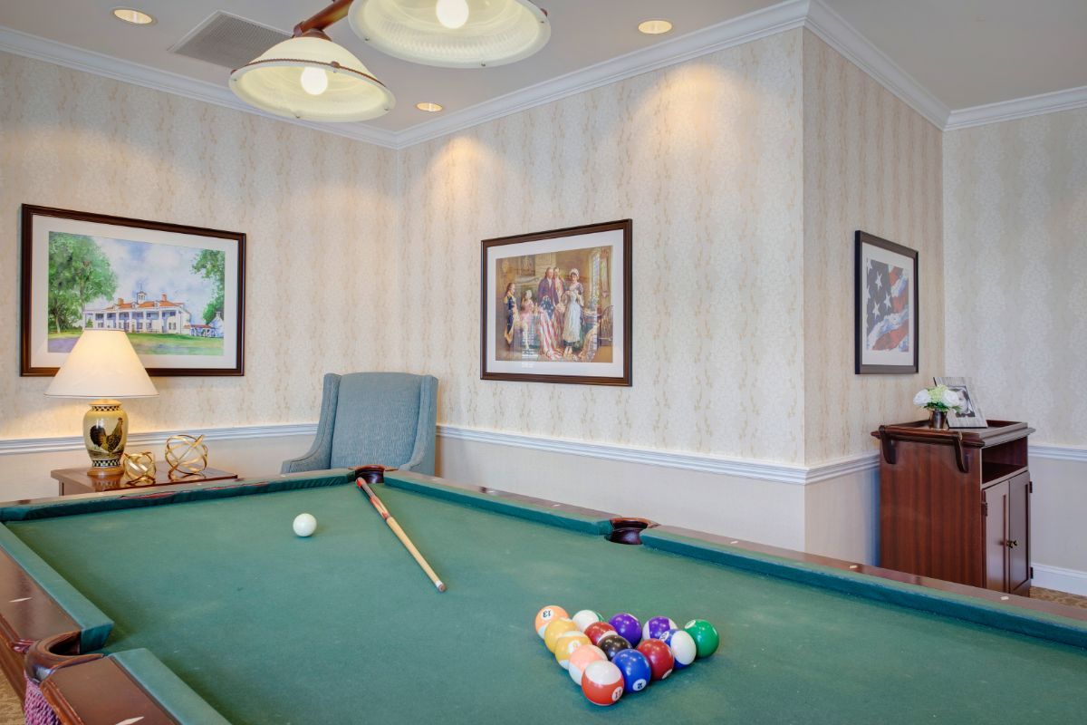 A well-decorated recreation room featuring a pool table with billiard balls and cues ready for play.