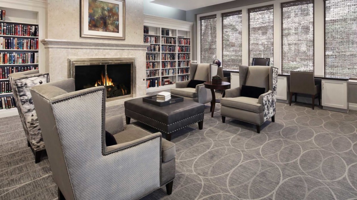 A cozy living room with a fireplace, armchairs, and bookshelves.