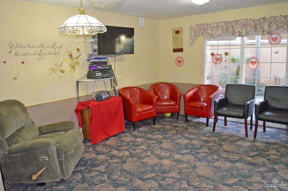 A cozy waiting room with red and gray chairs, a television, and decorative accents.