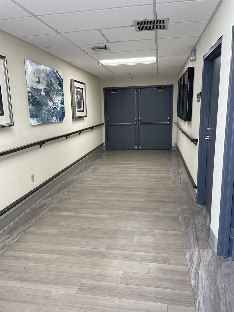 A hospital hallway with artwork and double doors at the end.