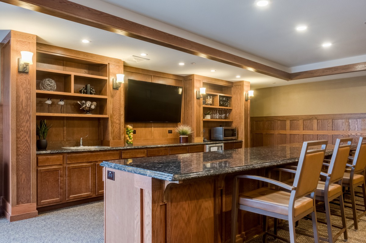 A modern kitchen interior featuring wooden cabinets and an island counter with bar stools.