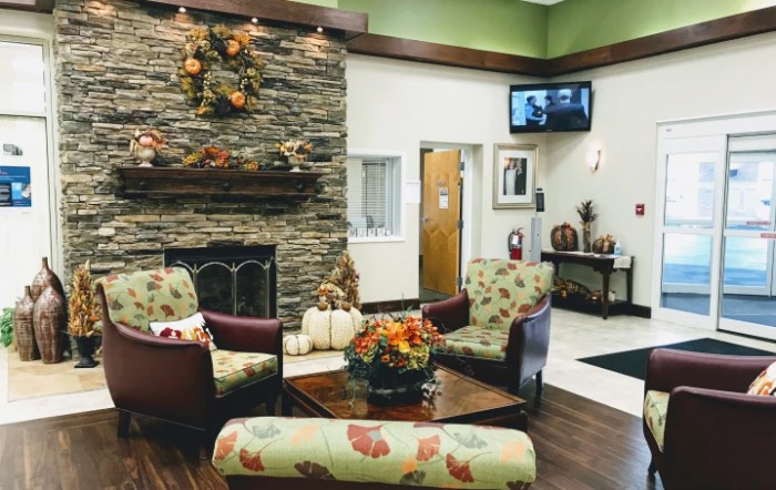 A cozy waiting room with a stone fireplace, autumn-themed decorations, and comfortable seating.