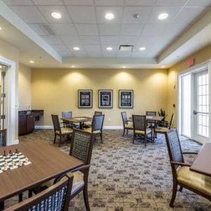A well-lit meeting room with neatly arranged tables and chairs on a patterned carpet.