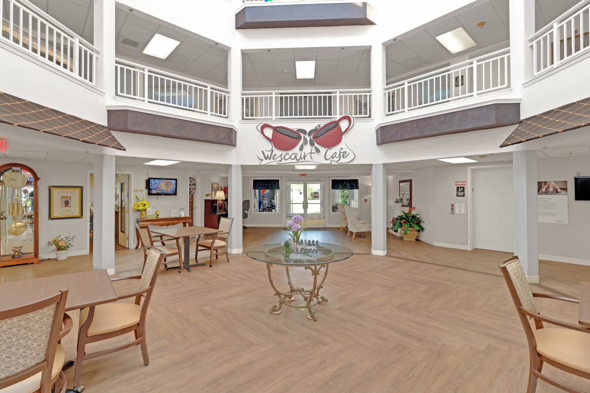 A spacious, bright lobby with furniture and an upper-level balcony.