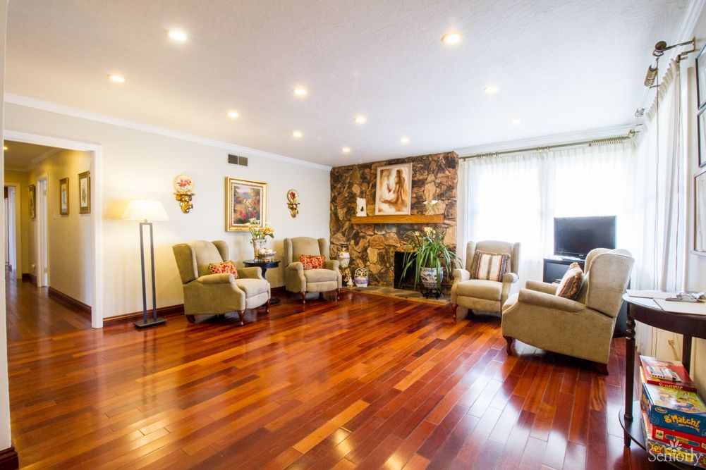 A spacious living room featuring a wooden floor, cozy seating area, and a stone fireplace adorned with decorative items.