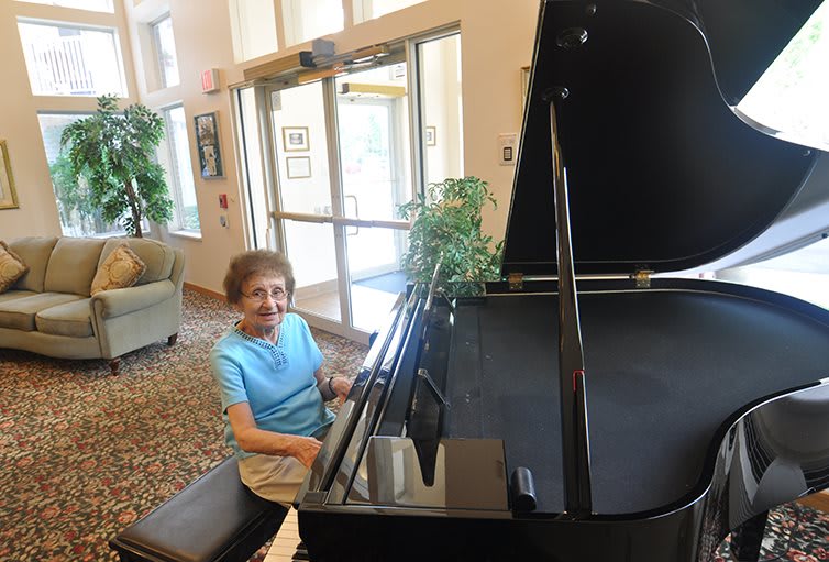 A woman playing the piano in a well-lit lobby.