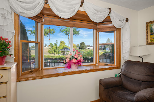 A cozy living room window adorned with elegant curtains, featuring a beautiful bouquet of flowers and a picturesque outdoor view.