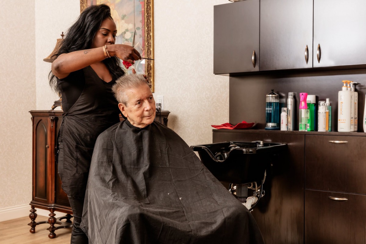 A hairstylist giving a haircut to an elderly client in a salon.
