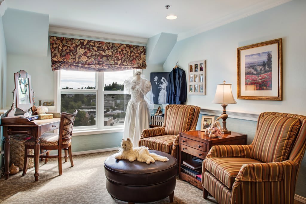 A cozy living room with armchairs, a mannequin, and a large window letting in natural light.