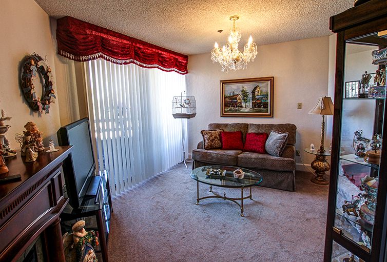 A cozy living room with classic decor featuring a chandelier, sofa, and coffee table.