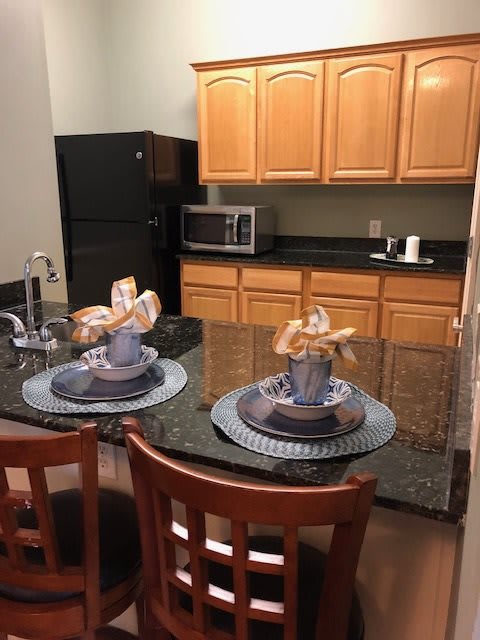 A cozy kitchen setup with a granite countertop, complete with decorative table settings and wooden cabinetry.