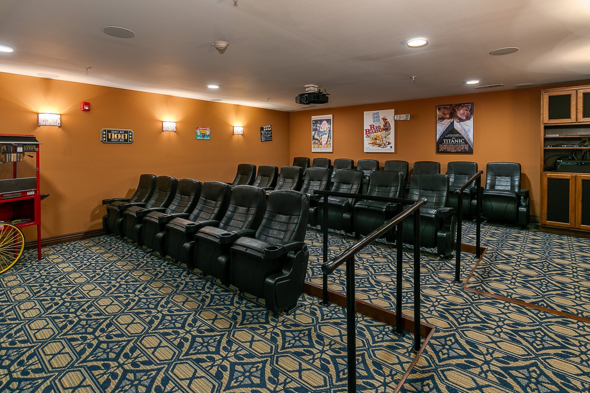 A cozy home theater room featuring tiered seating, a projector, and walls adorned with movie posters.