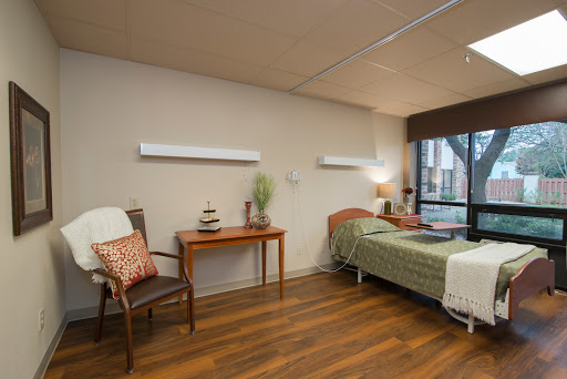 A well-lit hospital room featuring a bed, a chair, and decorative elements.