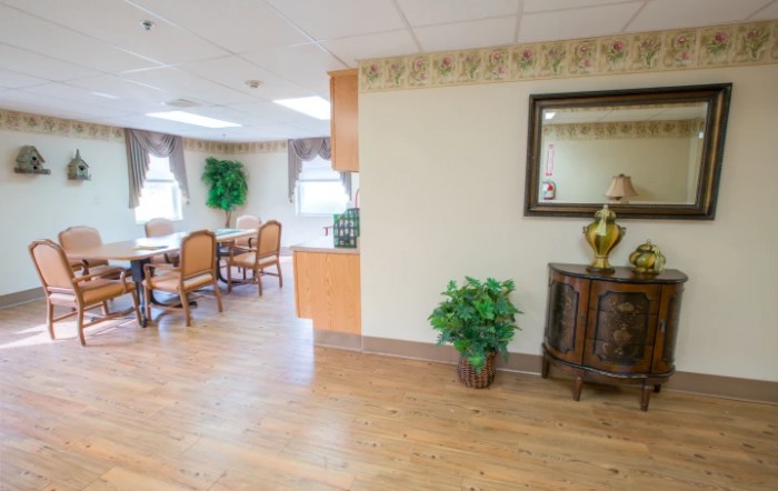 A cozy and well-decorated interior space featuring a dining area with wooden furniture, decorative plants, and a wall mirror.