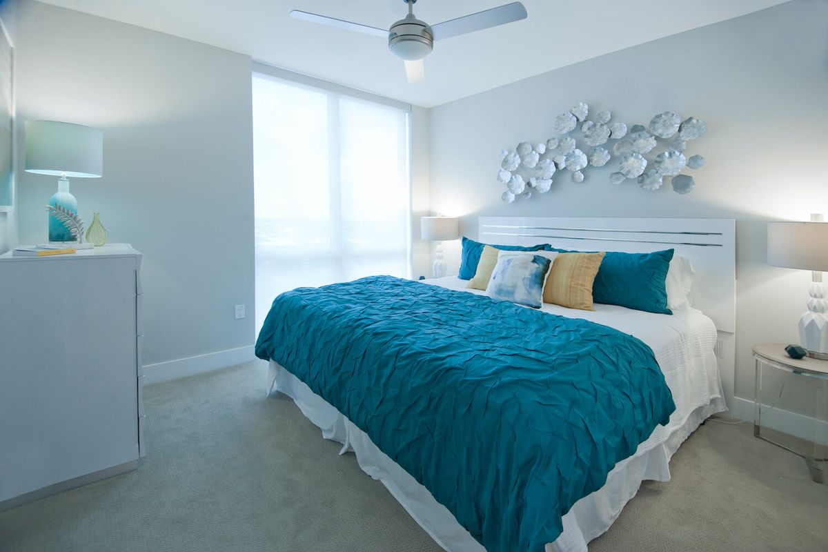 A modern bedroom with teal and white decor featuring a comfortable bed.